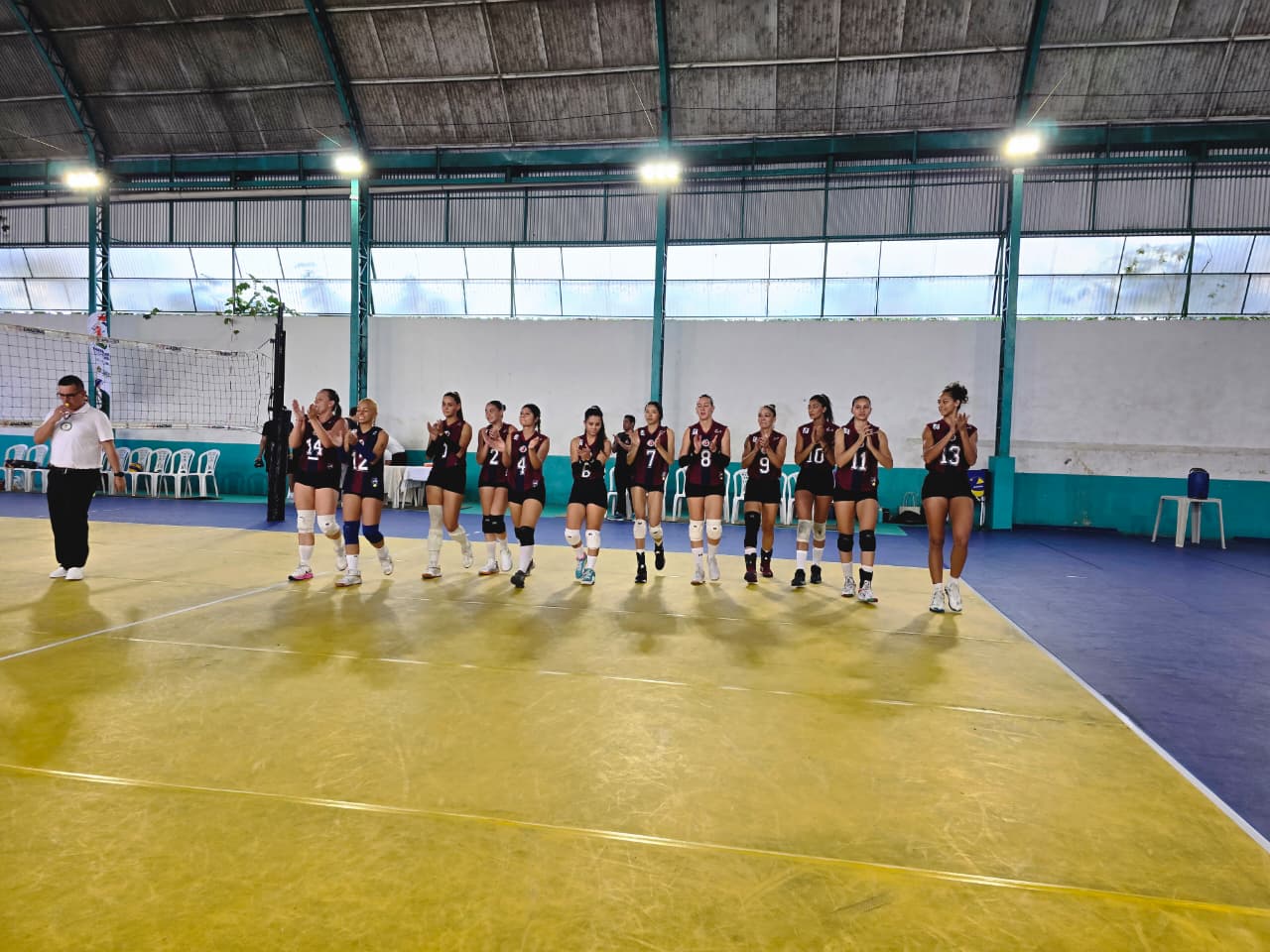 Equipe feminina da A.A. Nilton Lins perfilada em quadra aplaudindo a torcida